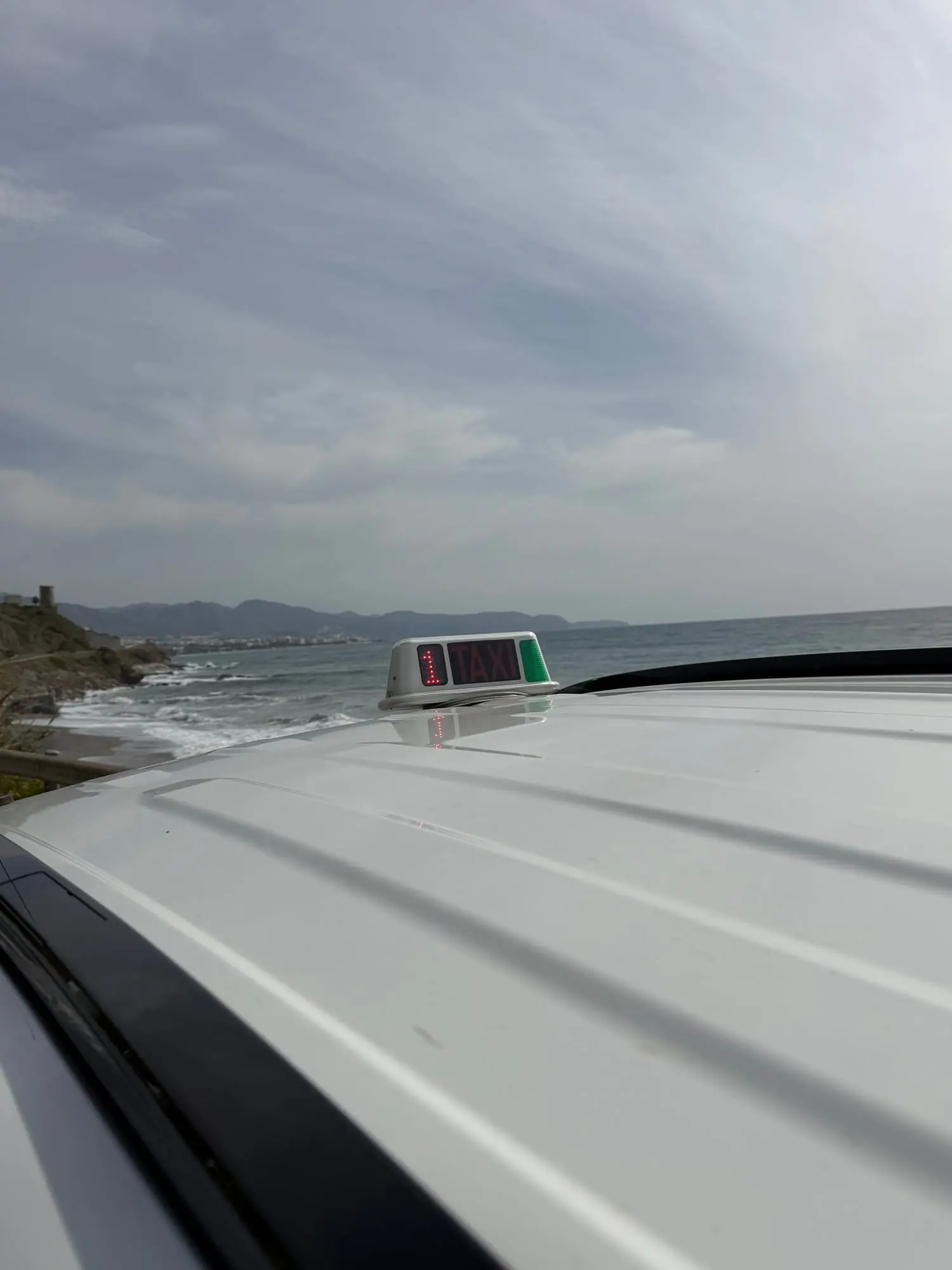 Módulo luminoso de taxi sobre el techo del taxi con el mar Mediterráneo al fondo